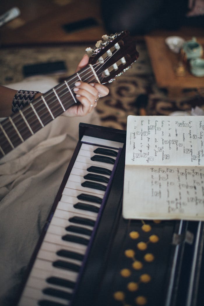 Home Close-up view of a guitar and keyboard with sheet music, capturing a cozy indoor music session.